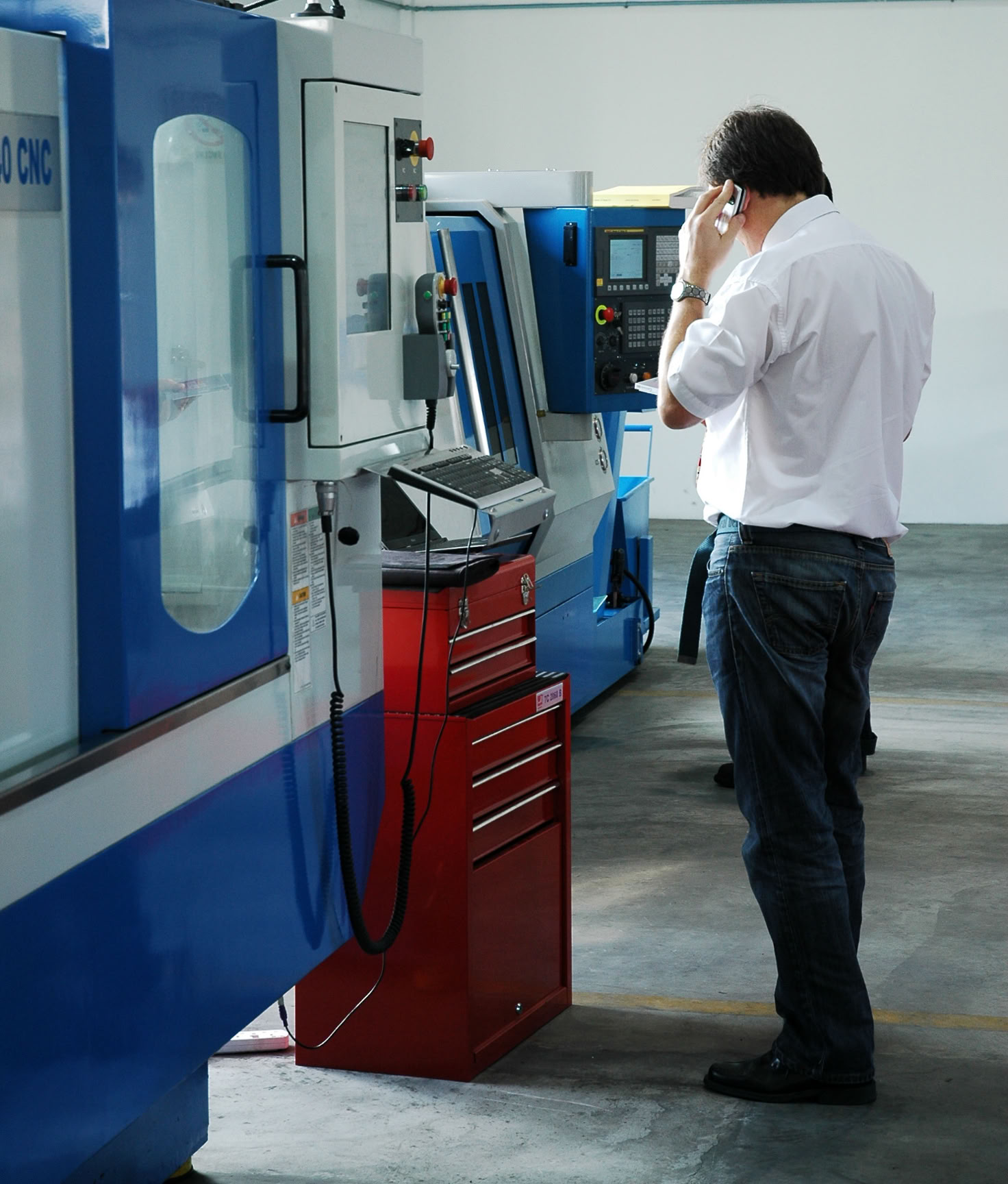 A CNC engineer stands beside a VMC